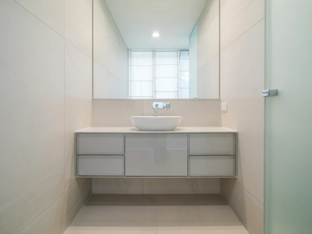 Compact bathroom with a gray wall mounted vanity and vessel sink under a large mirror.