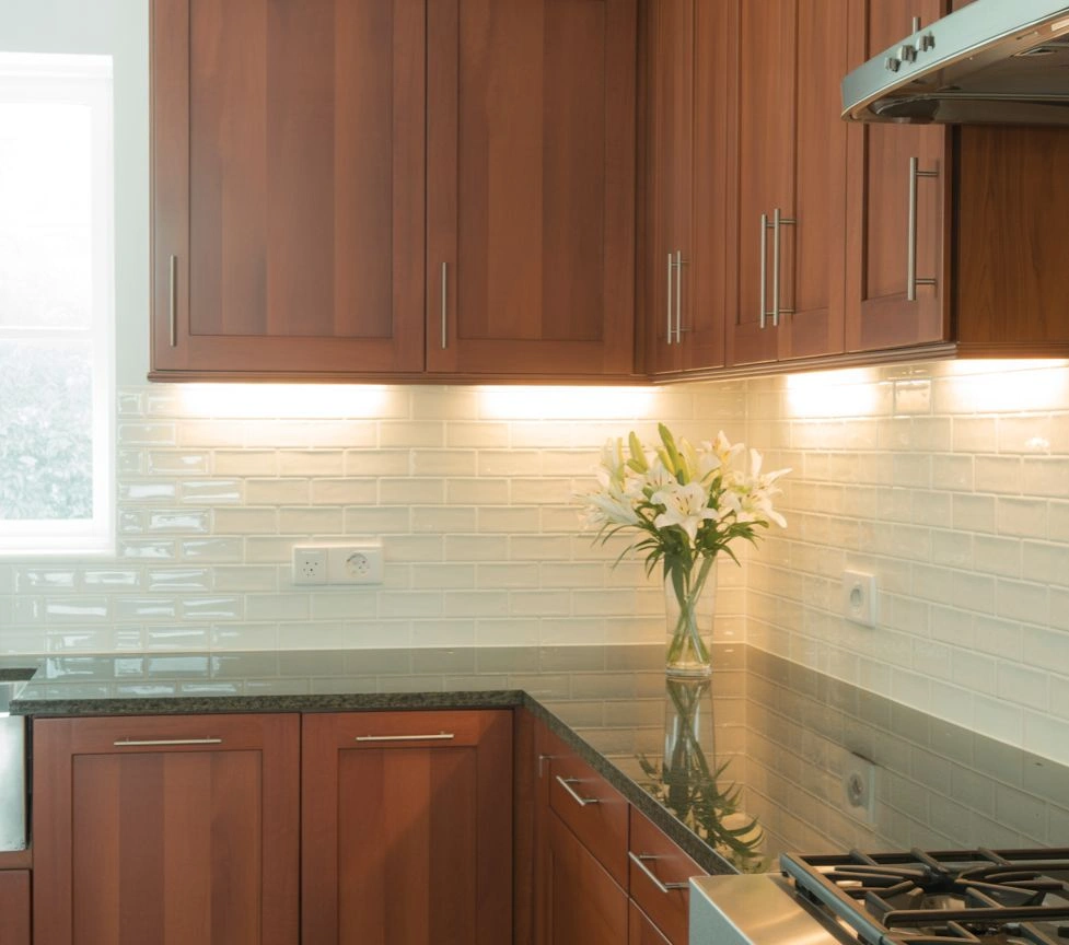 Light-colored backsplashes like white textured tile and creamy ceramic used to brighten and balance cherry wood kitchen cabinets.